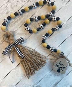 a wooden bead necklace with black and white buffalo plaid beads, tassels and a tag that says happy