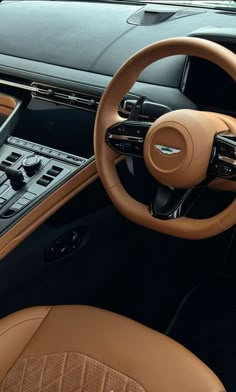 the interior of a luxury car with brown leather and tan stitching on the steering wheel