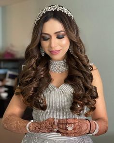 a woman with long hair wearing a tiara and holding her hands together