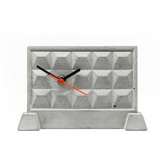 a clock made out of concrete blocks with an orange hands