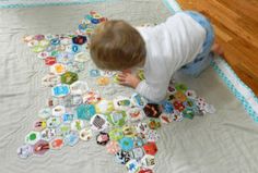 a toddler playing with buttons on a quilted star shaped bed spread in front of a wooden floor