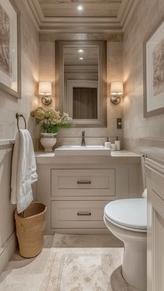 a white toilet sitting next to a sink in a bathroom under two framed pictures on the wall