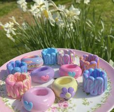 a pink plate topped with lots of different shaped doughnuts on top of a table