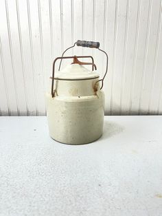 a white ceramic tea pot with a metal handle