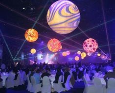 a large group of people sitting at tables in front of a stage with lights on it