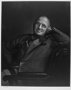 an old black and white photo of a man in a suit holding his hand up to his ear