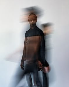 a blurry image of a man standing in front of a wall