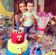 a woman holding a baby in front of a birthday cake