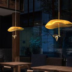 three lamps hanging from the ceiling in a restaurant with wooden tables and chairs around them