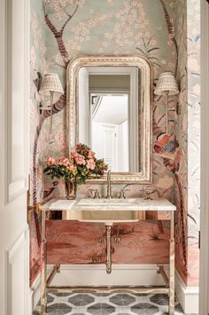 a bathroom with a mirror, sink and flowers on the counter in front of it