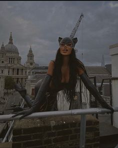 a woman in black catsuits on top of a building