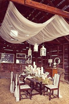 a dining room table with white drapes hanging from the ceiling