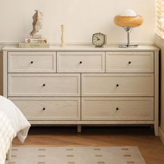 a bedroom scene with focus on the dresser and bed sideboard that has an alarm clock