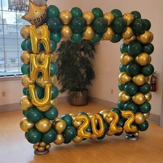 a large balloon arch in the shape of a number 20 with gold and green balloons