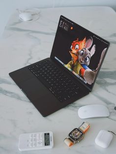 an open laptop computer sitting on top of a white table next to a mouse and cell phone