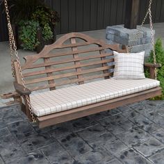 a wooden bench with two pillows on it and some plants in the backgroud