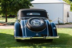 an antique car is parked in the grass