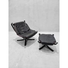 two black leather chairs sitting next to each other on top of a white floor covered in cement