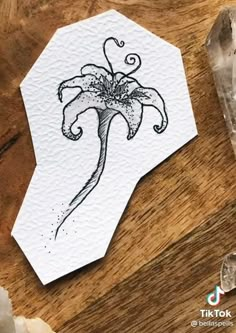 a piece of paper with a flower drawn on it next to some crystal stones and a knife