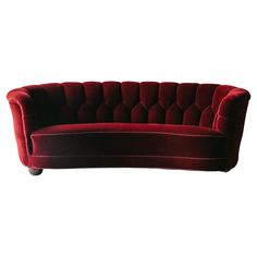 a red velvet couch sitting on top of a white floor