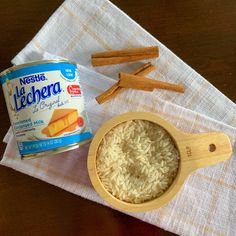 a can of rice and some cinnamon sticks on a napkin with a wooden spoon next to it