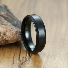 a black ring sitting on top of a wooden table next to a rock and tree branch