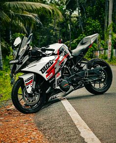 a white and red motorcycle parked on the side of a road next to palm trees