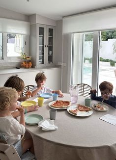 four children sitting at a table eating pizza