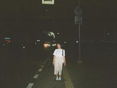 a woman is walking down the street at night