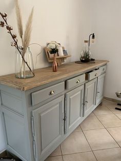 a large gray cabinet with two vases and flowers on it's top shelf