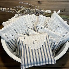 four pieces of white and blue striped cloth on a plate with lavenders in the background