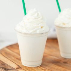 two cups filled with whipped cream on top of a wooden table