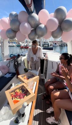 two women sitting on the back of a boat with balloons hanging from it's ceiling