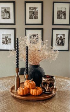 a wooden table topped with a black vase filled with flowers and pumpkins on top of it