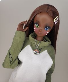 a doll wearing a green and white hoodie with cat's eyes painted on it