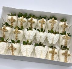 a box filled with lots of white chocolate covered strawberries and topped with gold crosses