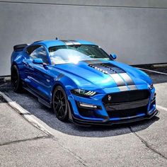 a blue sports car parked in a parking lot next to a gray and white building