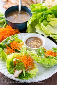 lettuce and carrots are on a plate with dipping sauce