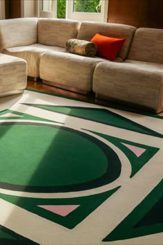 a living room with a large green and white rug on the floor next to a couch