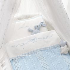 a baby crib with a teddy bear on it's side and a pillow in the middle