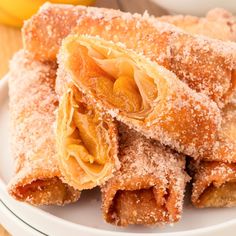 several pastries are stacked on a plate with powdered sugar and oranges in the background