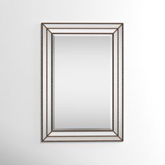 a mirror hanging on the wall next to a sink and toilet in front of a white wall