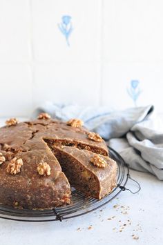 a chocolate cake with walnuts on top sitting on a wire rack