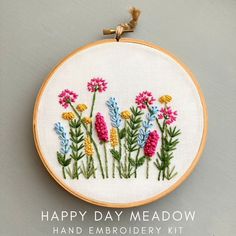 a embroidery kit with flowers on it that says happy day meadow