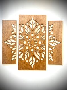 three wooden wall hangings with laser cut designs