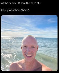 a man standing in the ocean with his shirt off and looking at the camera smiling