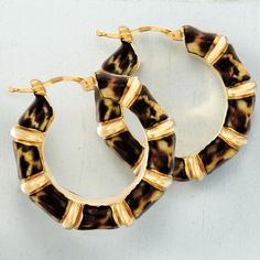 pair of tortoise shell hoop earrings with gold accents on white background, closeup