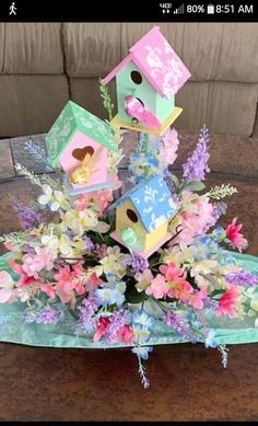 a bunch of bird houses sitting on top of a table with flowers in the middle