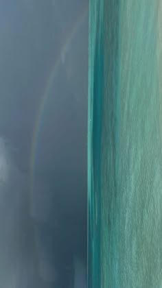 a rainbow appears over the ocean as seen from an airplane