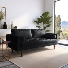 a living room with a black leather couch and large glass doors leading to the outside